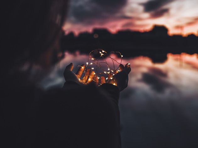 Photography tip: Add props. Dark photo of a person holding Christmas lights. 